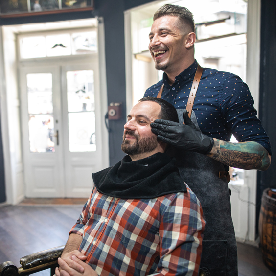 Ein Mann sitzt beim Friseur und bekommt die Haare geschnitten.