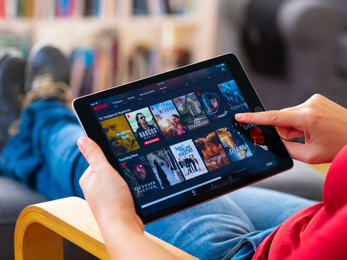 Eine Person bedient ein Tablet auf dem die Netflix App geöffnet ist.