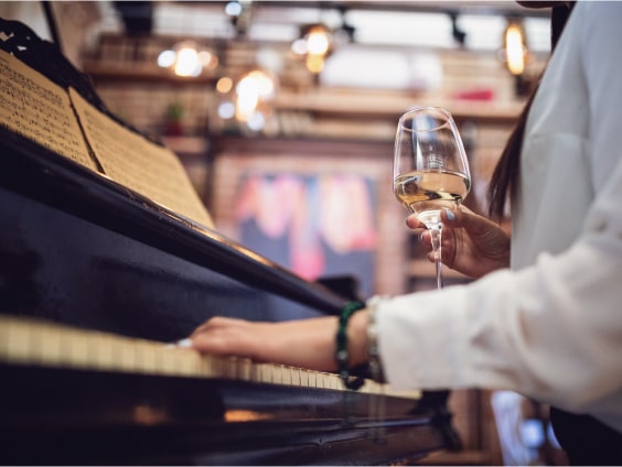 Frau mit Weinglas an Piano