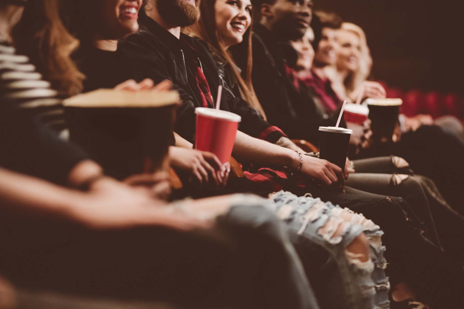 Personen sitzen im Kino mit Popcorn und Getränken