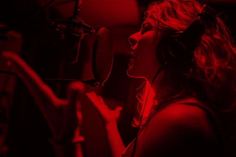 Eine Sängerin in rot beleuchteter Umgebung.