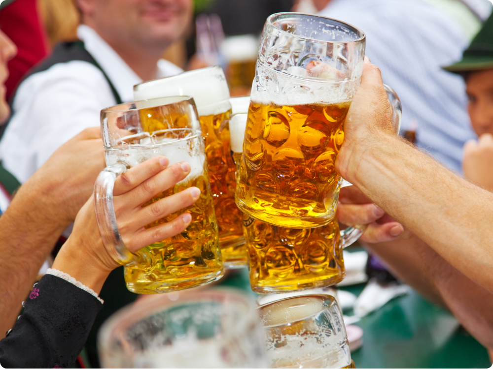 Mehrere Hände stoßen mit großen Bierkrügen voller Bier an.