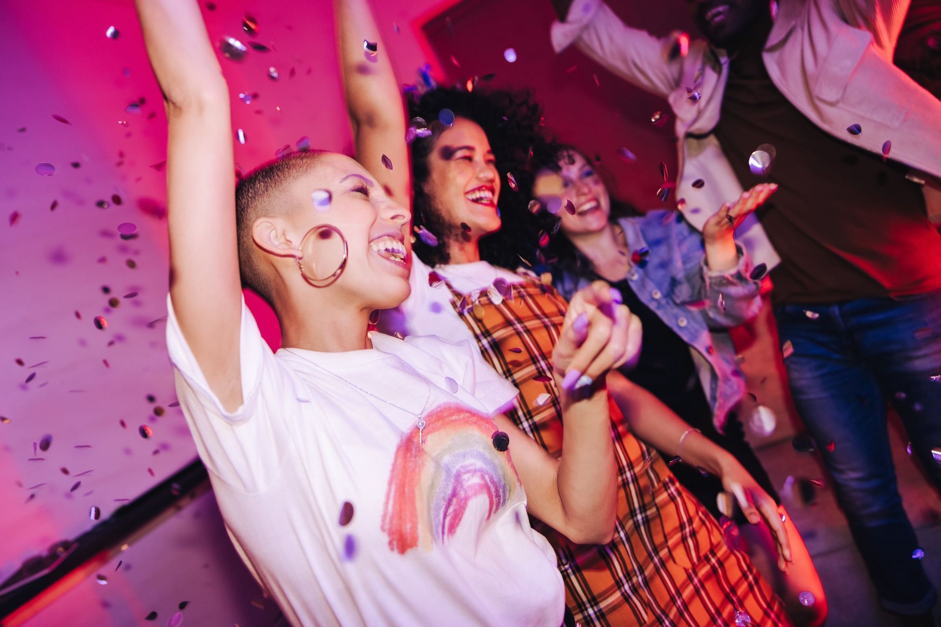 Gruppe von Frauen, die mit erhobenen Armen und Konfetti in der Luft feiern.