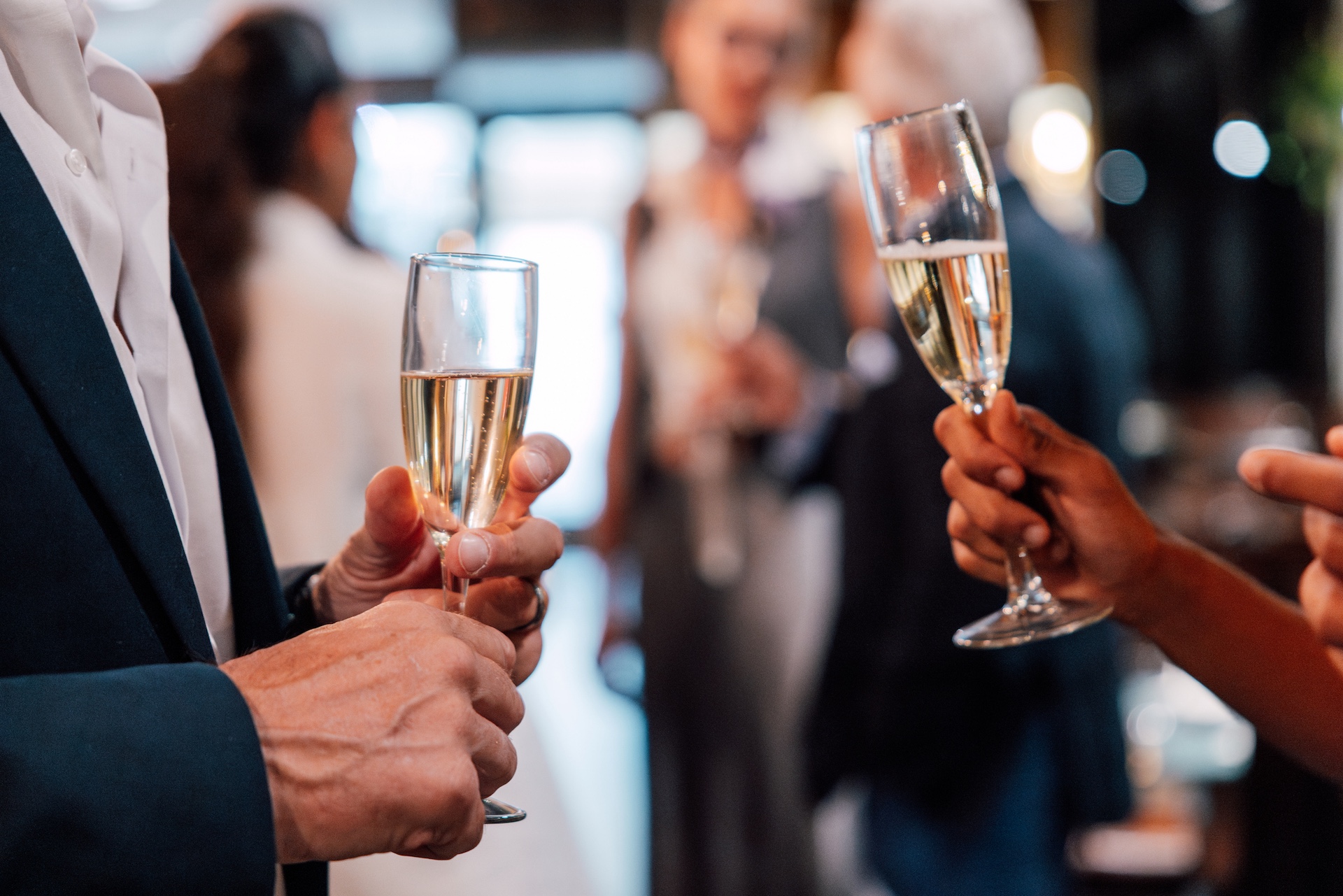 Zwei Personen halten Sektgläser in einer geselligen Umgebung.