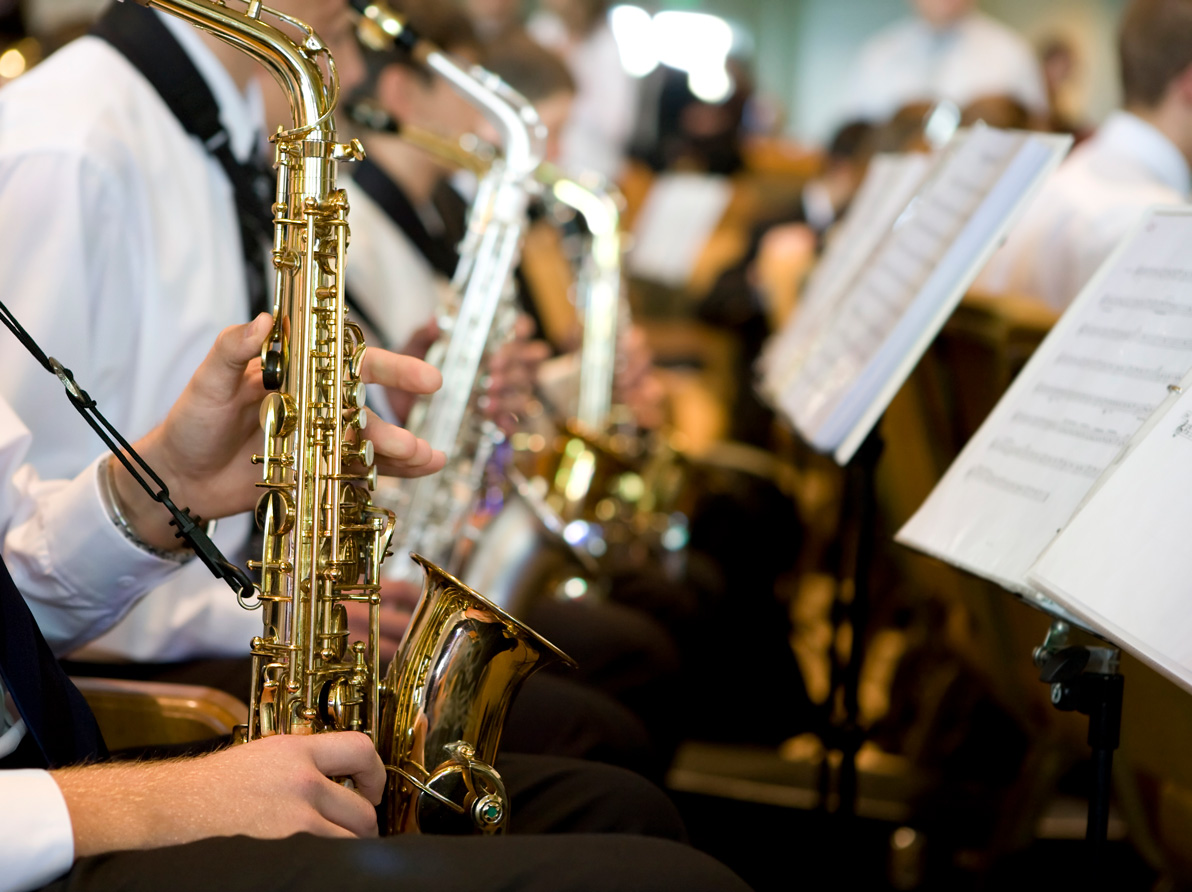 Musiker spielen Saxophone in einer Reihe, Notenständer davor.