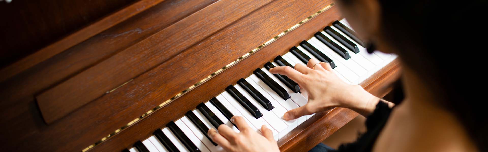 Hände spielen auf einer Klaviertastatur aus Holz.