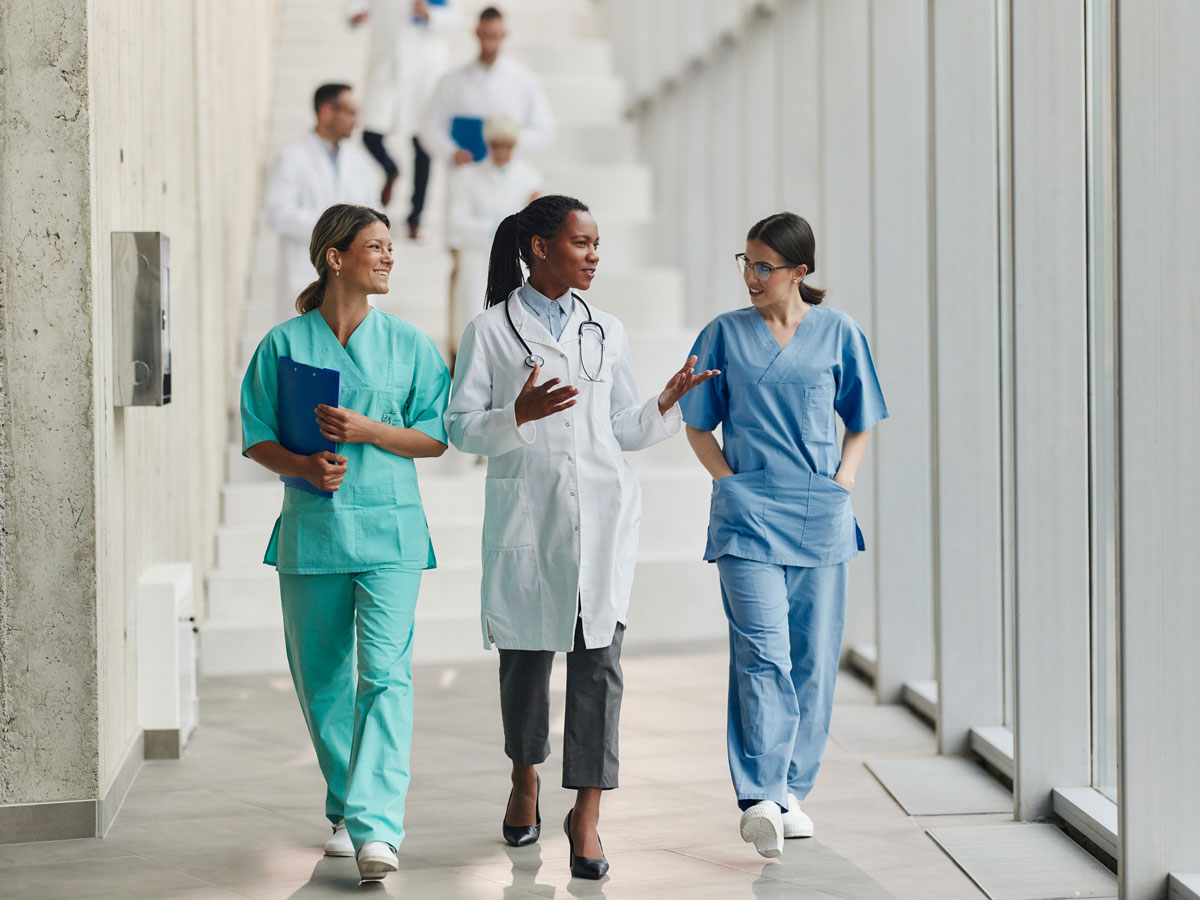 3 Ärztinnen laufen im Krankenhaus den Flur entlang