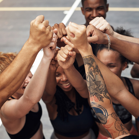 Eine Gruppe Sportler strecken ihre Fäuste gemeinsam in die Höhe.