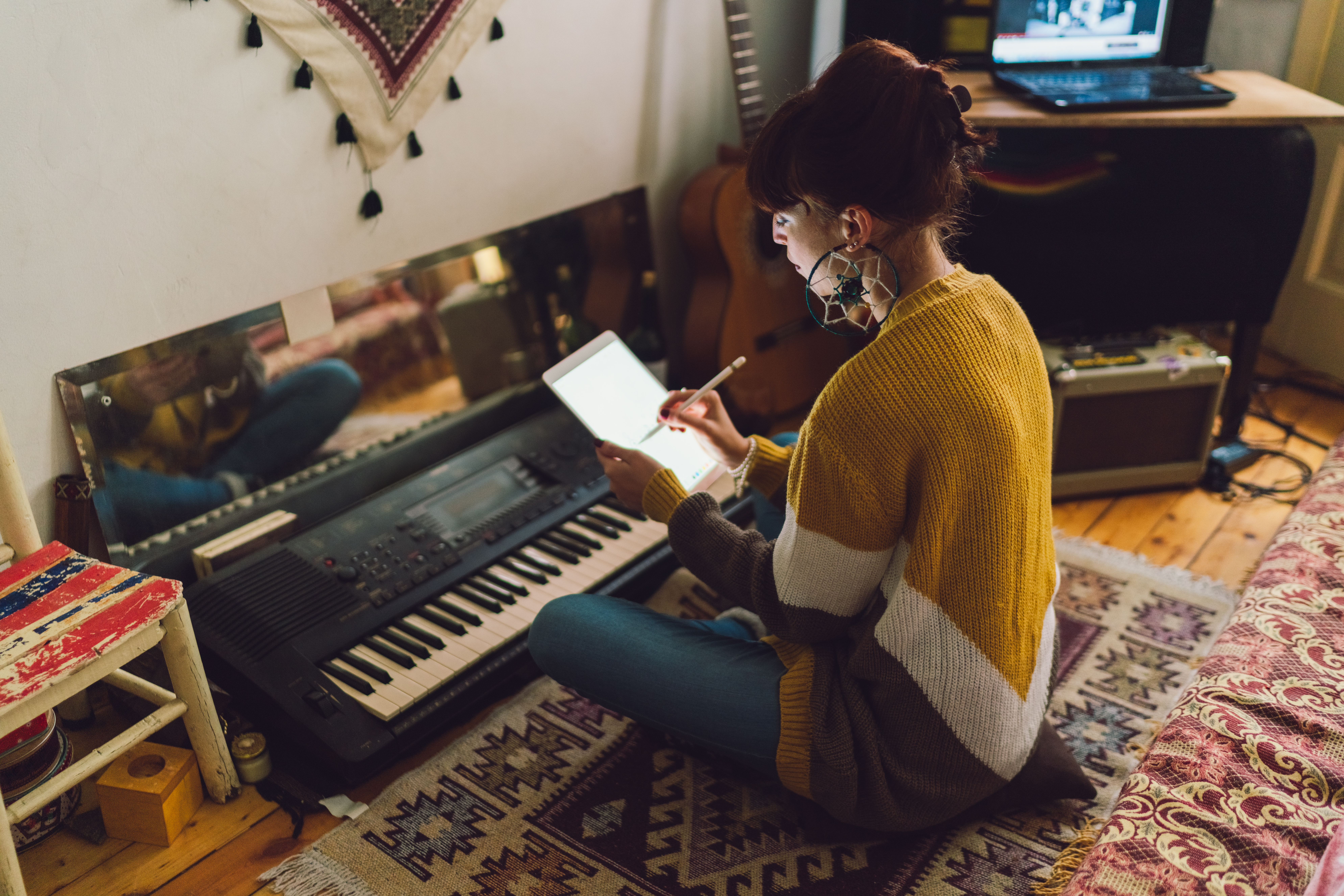 woman with ipad in front of pianoFrau tippt am ipad vor Klavier sitzend