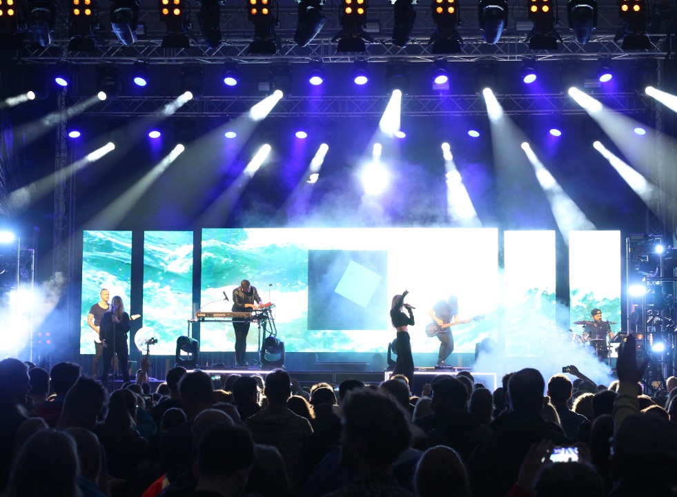 Eine Band tritt auf einer in blauem Licht bestrahlten Bühne auf.