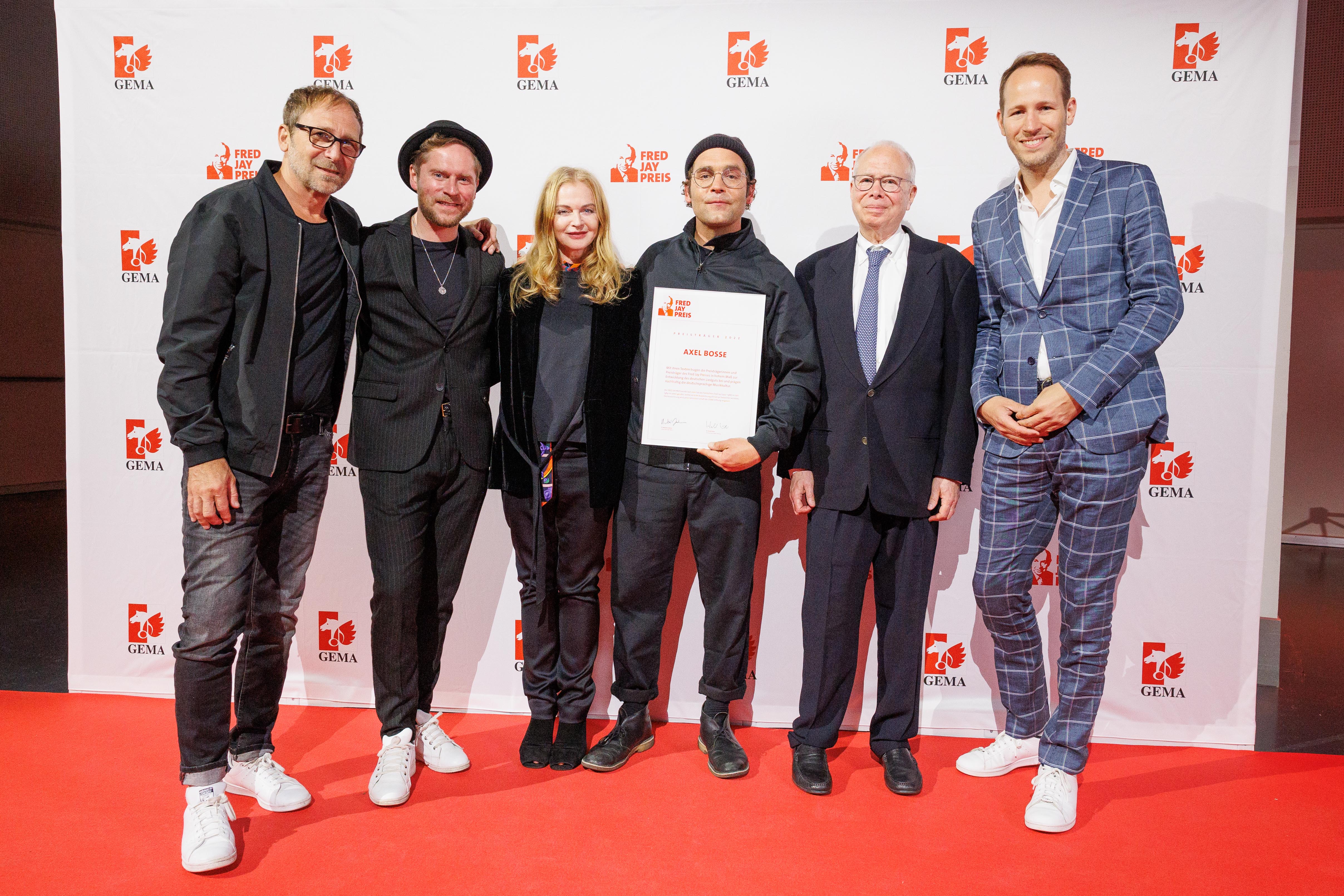 Axel Bosse mit Jury und Stifter auf dem roten Teppich vor einer Pressewand