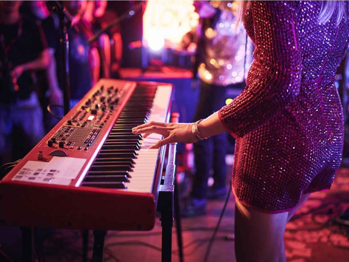 Frau spielt in einem Kleid auf einer Bühne Keyboard