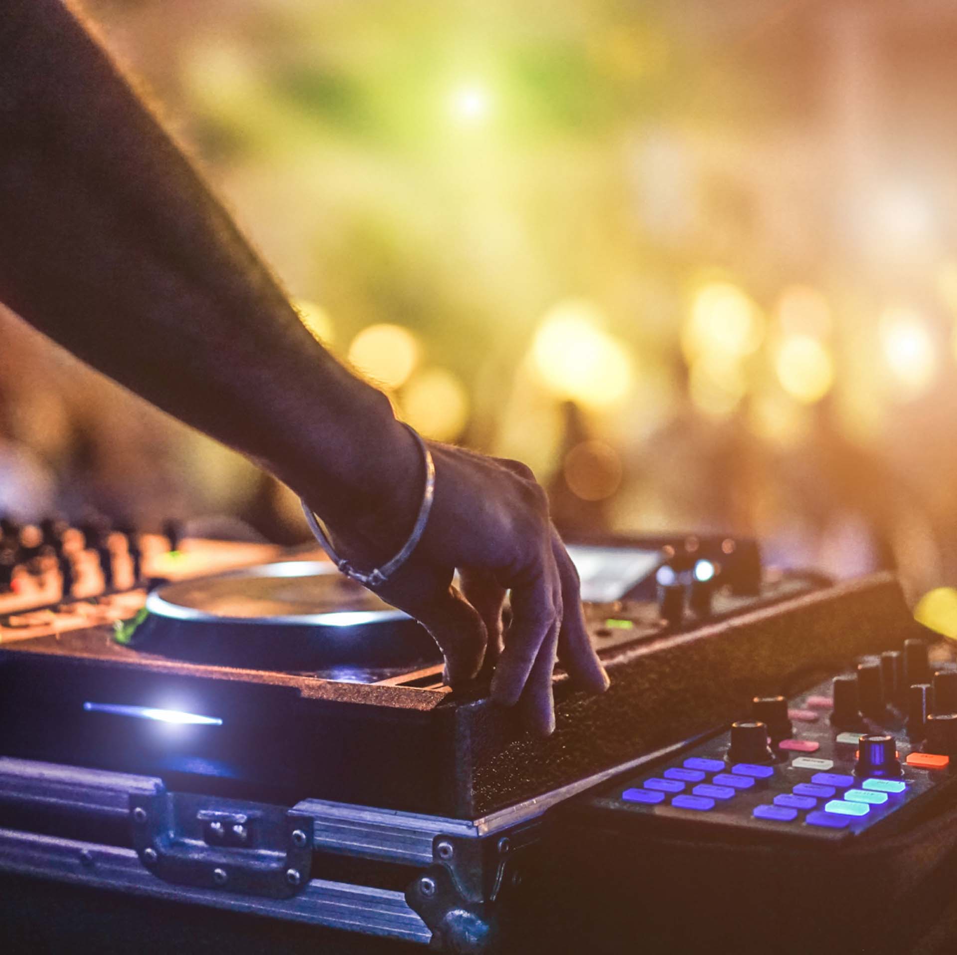 Eine Person bedient ein DJ Pult auf einem Festival.