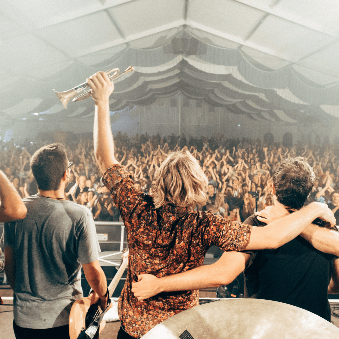 Eine Band posiert vor einer applaudierenden Menge.