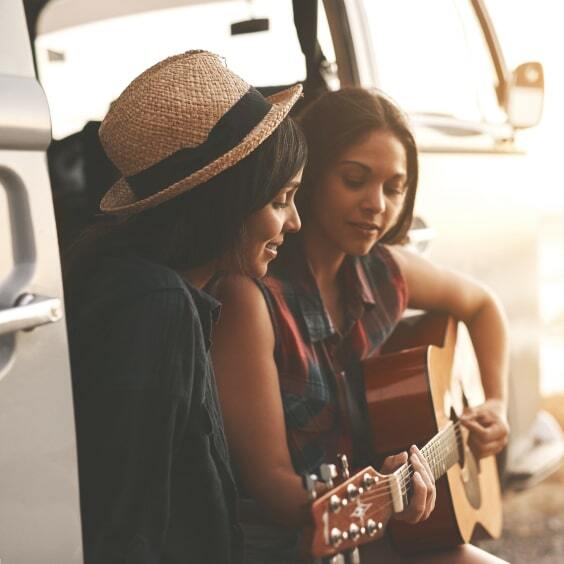 Zwei Frauen sitzen in einem Bus und spielen auf einer GItarre